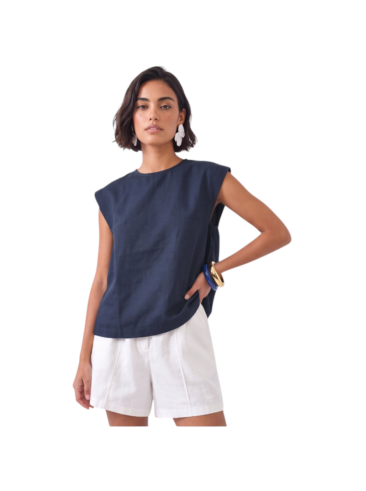 Model wearing a navy blue K/Woods Ember Top with cap sleeves and center-neck gathers, paired with white shorts.