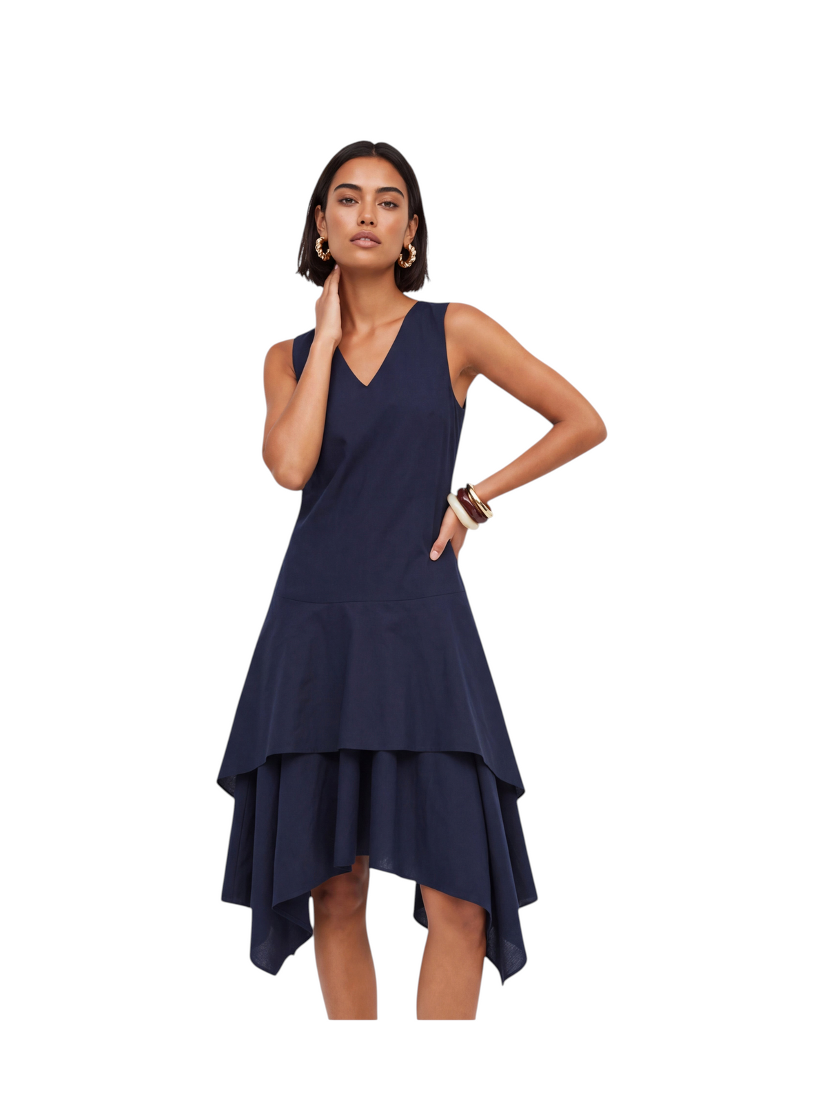 A model wearing a navy blue K/Woods Solstice sleeveless dress with a keyhole neckline and tiered handkerchief hem.